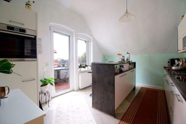 Einbauküche mit Tresen und Zugang zum Balkon - Wohnung 1.OG links