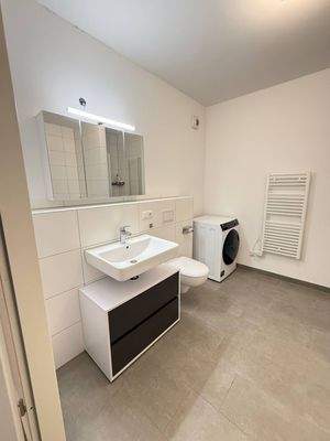 Badezimmer mit Dusche und Badewanne,  weiß gefliest mit grauem Fliesenboden, .jpg