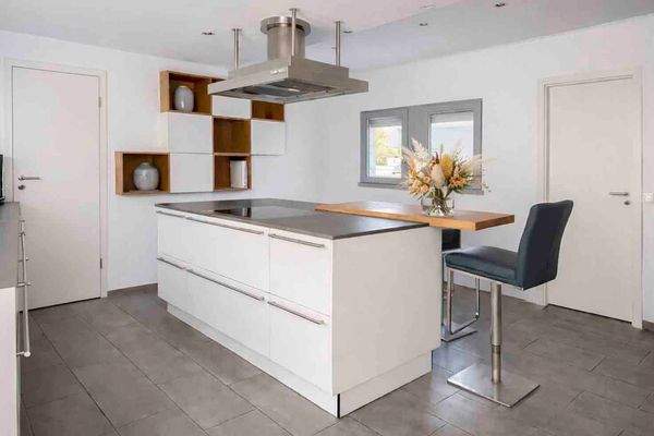 Helle Wohnküche mit Kochinsel und HWR Zugang links