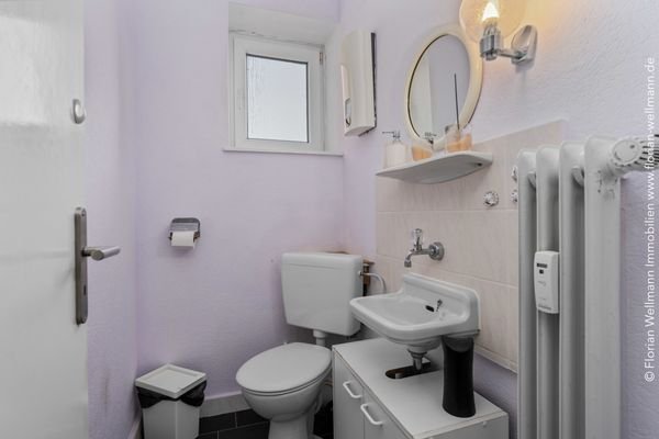 Separates WC mit Waschbecken und Fenster.