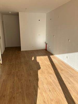 Wohn-Koch-Essbereich mit Blick Richtung Küchenbereich; weiß angelegte Wände und brauner Vinyl-Designboden in Holzoptik