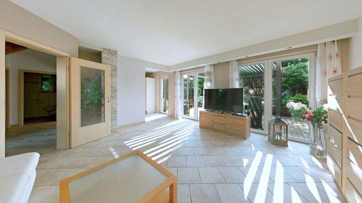 Wohnzimmer mit Zugang zum Ess-Küchenbereich und Garten