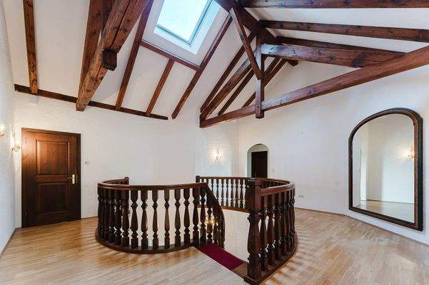 Die Galerie verbindet Etagen – mit Blickfang-Holzstruktur und luftiger Raumhöhe