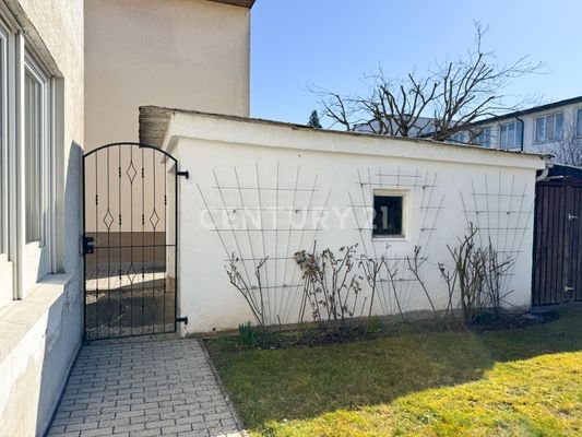Gartentor zur Garage mit duftenden Rosen im Sommer