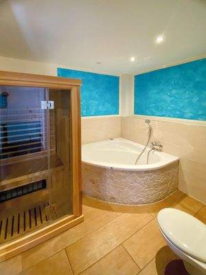 Badezimmer mit Eckbadewanne, Dusche und Sauna