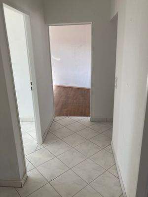 Flur mit weiß angelegten Wänden und grau-weißen Bodenfliesen