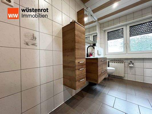 EG: Badezimmer mit hellen Fliesen, schönem Holz und klarer Struktur