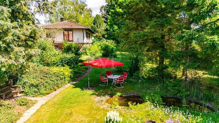 Blick auf die Villa vom Gartenteich mit Sitzplatz