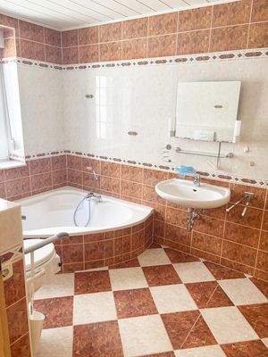 Wannenbadezimmer mit Fenster, Dusche und behindertengerechter Toilette