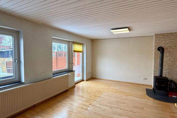 Das Wohnzimmer mit Ofen und Zugang zur Terrasse.