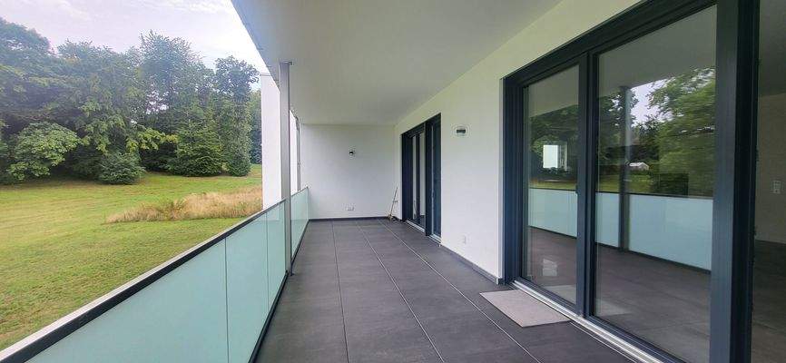 GROSSER ÜBERDACHTER BALKON MIT BLICK INS GRÜNE