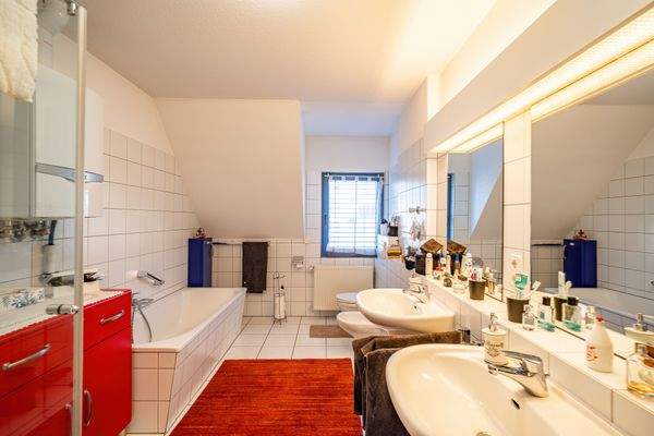 Das Bad ist weiß gefliest und mit Badewanne, Glasdusche und Bidet ausgestattet. 