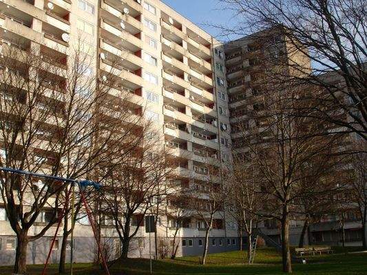 Gartenansicht eines mehrgeschossigen Wohnhauses mit Loggien und Bepflanzung