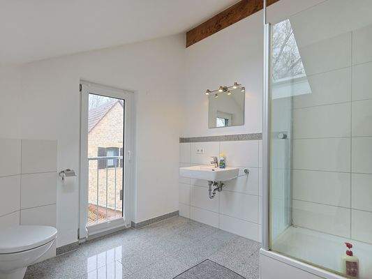 Hell gefliestes Tageslichtbadezimmer mit Duschkabine und WC