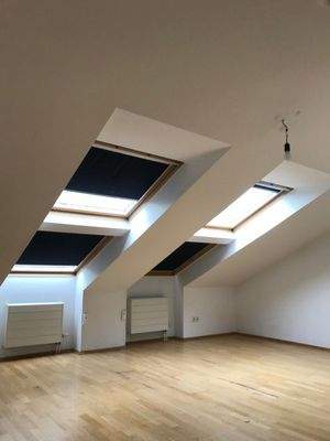 Schlafzimmer mit weißen Wänden und Parkettboden. Dachschräge mit zwei Dachfenstern