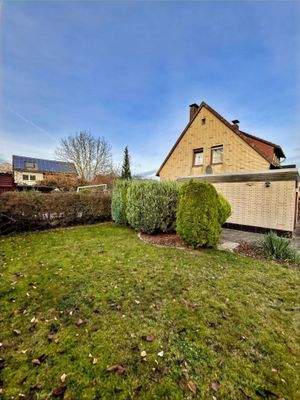 Kleine Rasenfläche und Blick auf die Westseite des Hauses und die Garage