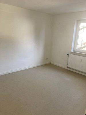 Schlafzimmer mit weiß angelegten Wänden und hellem Linoleumboden