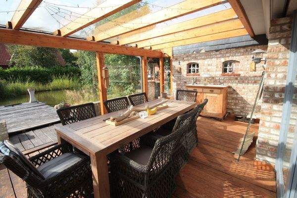 überdachter Terrassenbereich mit Blick auf Terrasse und Gartenteich