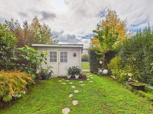 Blick in den Garten mit Gartenhäuschen und Gartentor