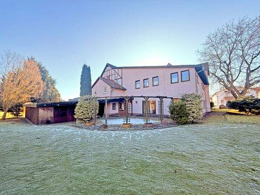 Blick aus dem Garten auf die große Terrasse und das Haus