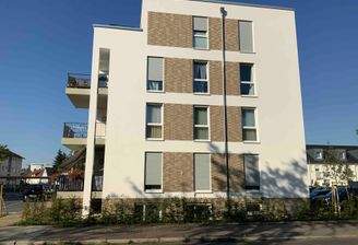 Außenansicht seitlich des 4 stöckigen Wohngebäudes von der Straße aus mit braunen Ziegelsteinmustern zwischen den Fenstern_ links Balkone zur Straße zeigend und rechts Stellplätze.JPG