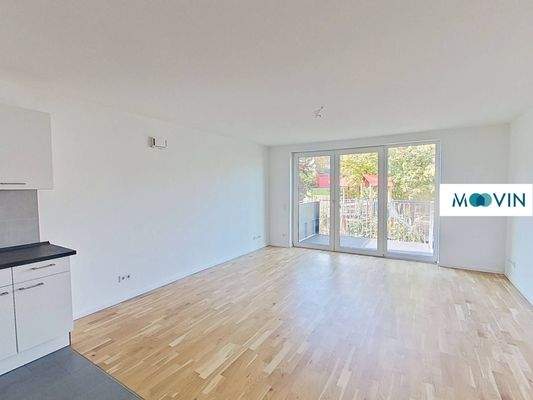 Ansicht I: Wohn- und Esszimmer mit offener Küche und Zugang zum Balkon