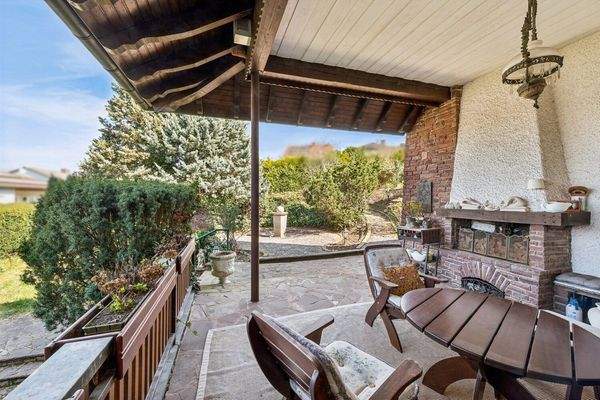 Exklusive Außenterrasse mit Kamin und freiem Blick ins Grüne.