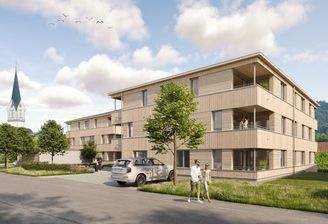 Mehrfamilienhaus in Holzbauweise mit Balkonen, darunter eine Person schlendert und ein Auto geparkt ist (Riedstrasse, Hohenweiler).