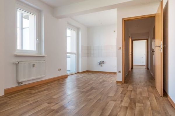 Wohnzimmer mit offener Küche und Balkonzugang