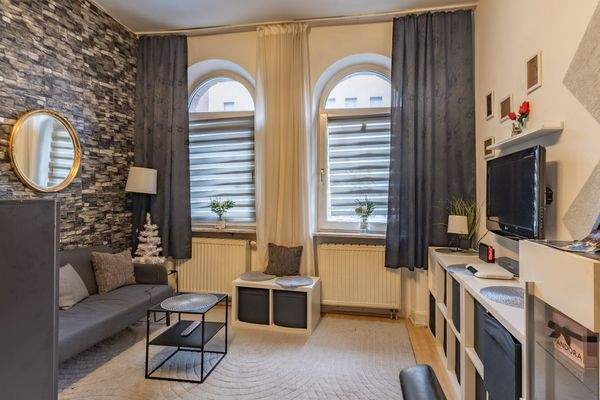 Wohnbereich mit charaktervollen Rundbogenfenstern und warmem Licht | Wohnung im Erdgeschoss