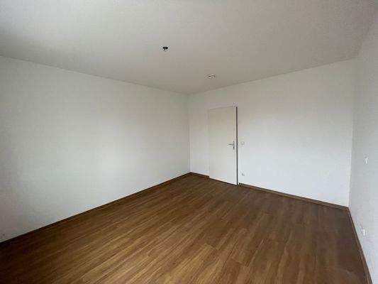 Kinderzimmer, brauner Laminatfußboden und weiß gestrichene Wände