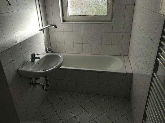 Bad mit Fenster und weißen Fliesen und weißen Sanitärobjekten