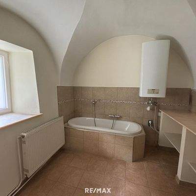 Helles Badezimmer mit Badewanne und Fenster