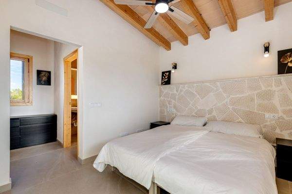 Schlafzimmer mit dekorativem Naturstein-Kopfteil, Deckenventilator und Bad en Suite