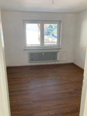 Schlafzimmer mit weiß angelegten Wänden und braunem Vinyl-Designboden in Holzoptik