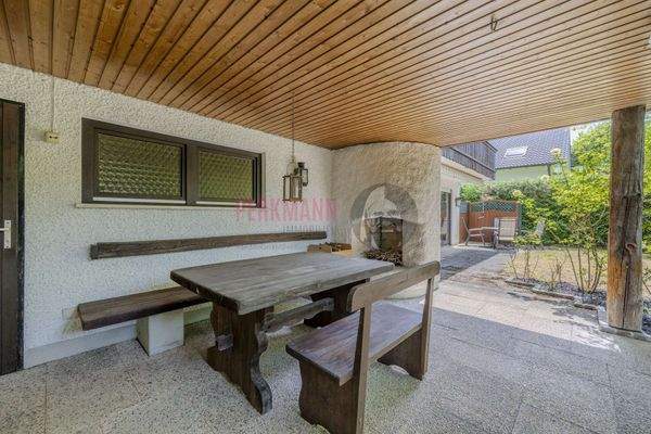 Sitzgarnitur im überdachten Freisitz mit offener Feuerstelle