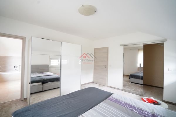 Schlafzimmer mit begehbarem Kleiderschrank sowie Zugang zum Badezimmer