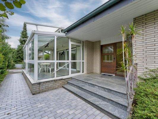 Hauseingang mit überdachtem Zugang und Wintergarten