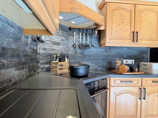 ...gemauerter Dunstabzugshaube und Schieferplattenrückwand.