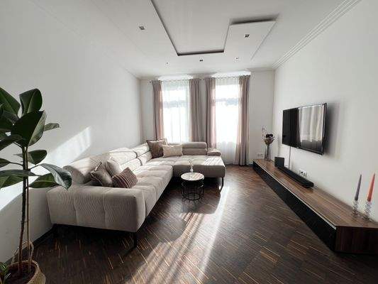 Heller Wohnbereich mit integrierter Deckenbeleuchtung, hohen Decken und Stuck