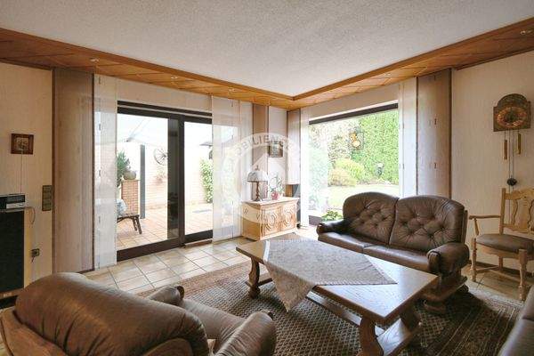 Das Wohnzimmer mit Blick auf die überdachte Terrasse und in den Garten