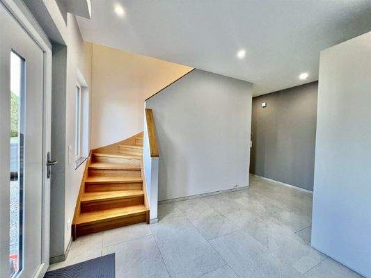 Großzügiger Empfangsbereich mit Holztreppe in das 