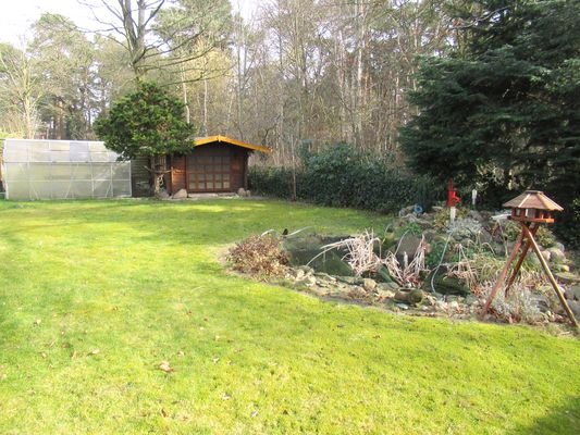 Gartenansicht mit Holzgerätehaus am Waldrand