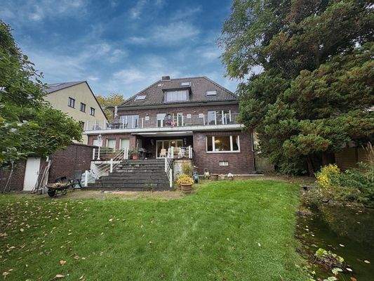 Gartenansicht mit Blick auf den Balkon und die Terasse und Garagenzugang