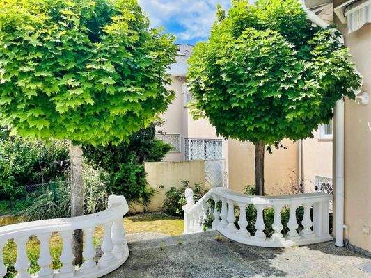 Kugelbäume umgeben die Terrasse und die Treppe zum Garten