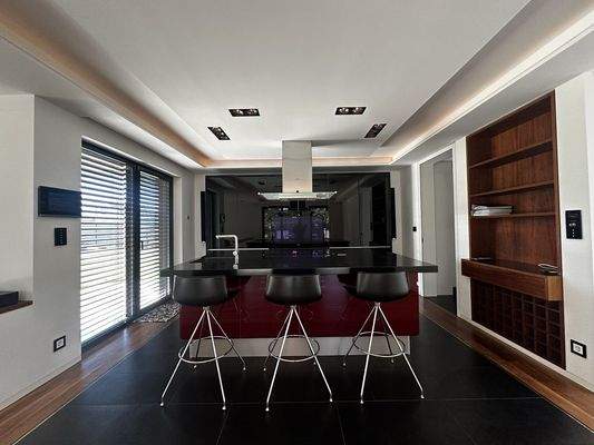 Blick auf die Einbauküche mit Kochinsel und Barhockern