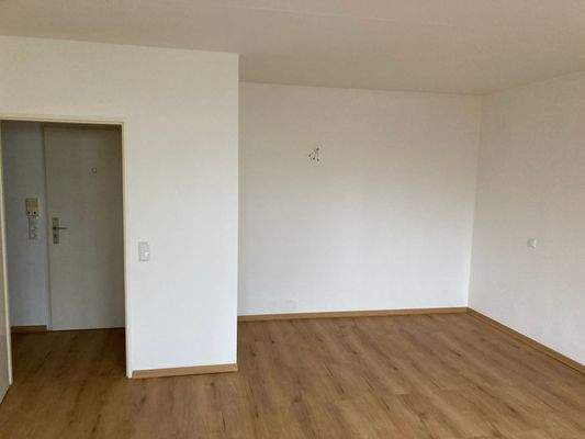 Wohnraum aus anderer Perspektive, weiße Wände und Boden in Holzoptik