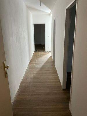 Flur mit Blick zu den Zimmern, Venylboden in Holzoptik und weißen Wänden.jpg