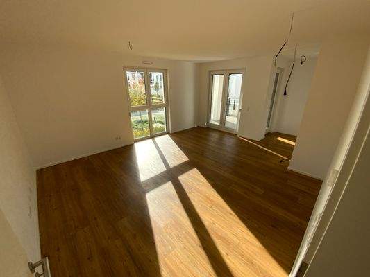 Wohn- und Essbereich mit weißen Wänden, Vinylboden in Holzoptik, Fenstern